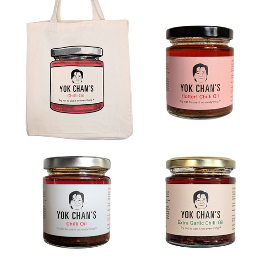 A cream canvas tote bag printed with a jar of Yok Chan's Chili Oil, shown alongside three glass jars of Yok Chan's chili oils (Chili Oil, Hotter Chili Oil, and Extra Garlic Chili Oil) on a plain white background.
