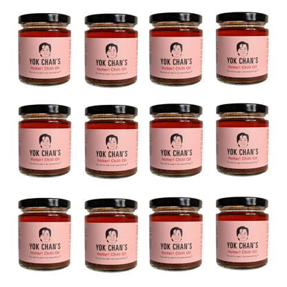 Twelve glass jars of Yok Chan's Hotter Chili Oil arranged in a 3x4 grid on a plain white background. Each jar has a pink label with a black lid and shows the brand name and product name clearly.