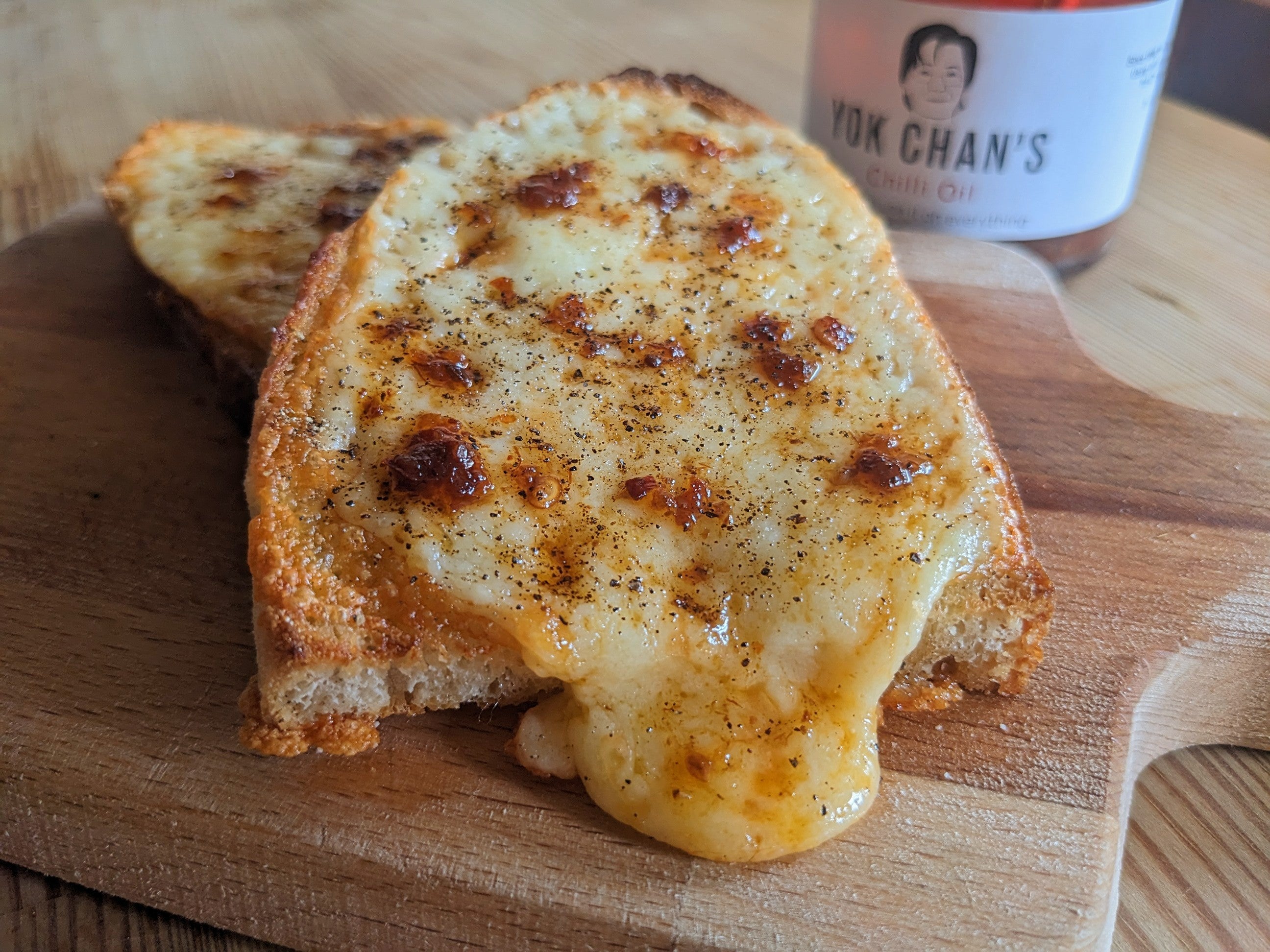 cheese on toast with pepper and chilli oil on a chopping board