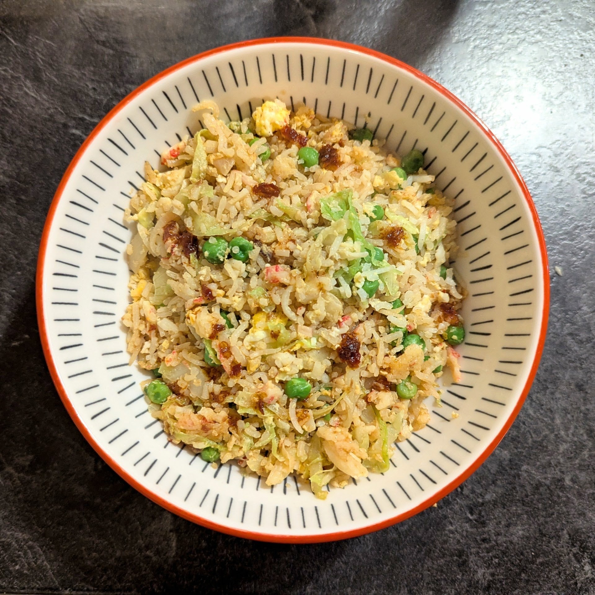 Bowl of fried rice with vegetables on a dark surface