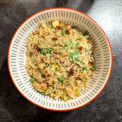 Bowl of fried rice with vegetables on a dark surface